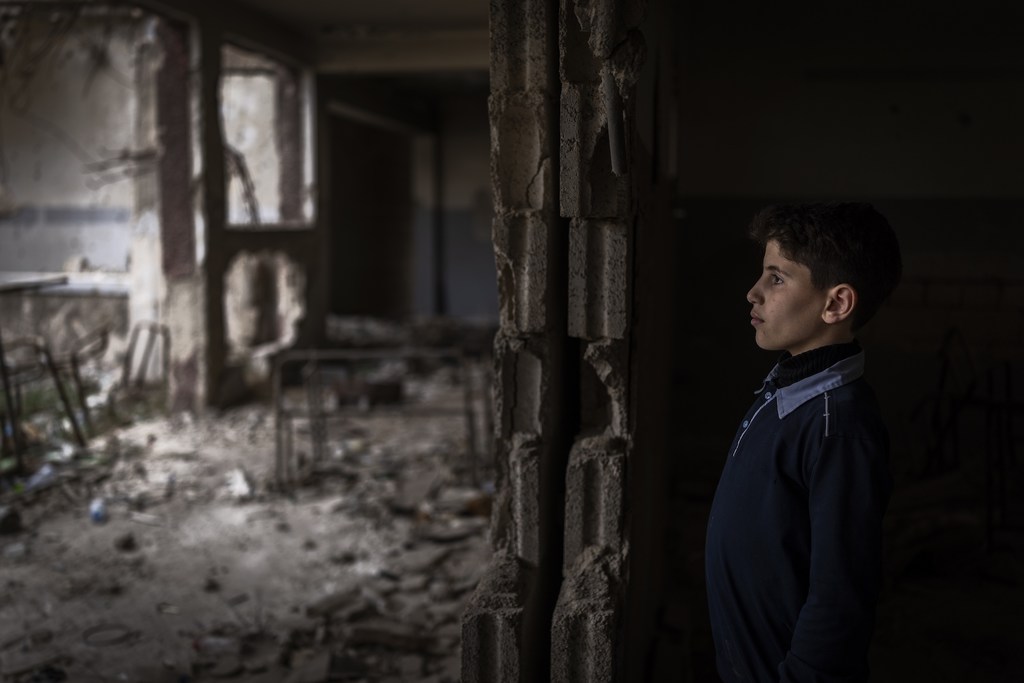 A young boy stands amid the ruins of a classroom in Douma destroyed during the Syrian civil war.